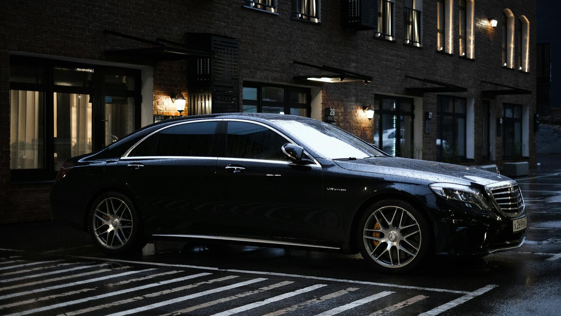 Zwarte Mercedes sedan op een natte straat in de avond
